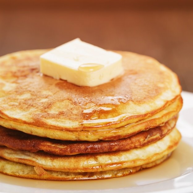 Buttermilk pancakes drizzled with syrup and topped with butter